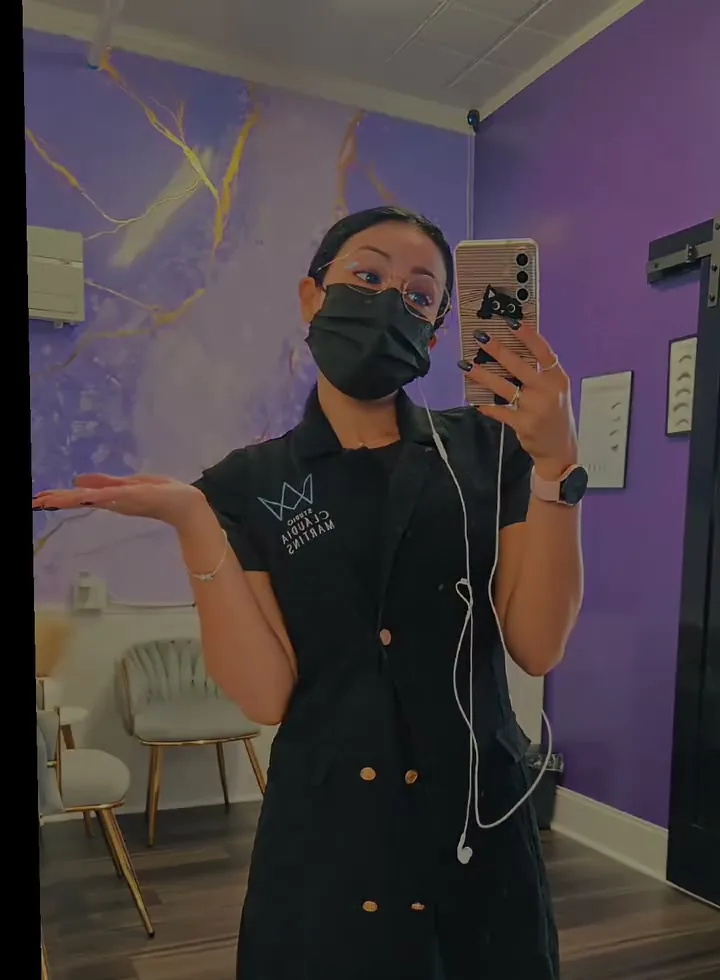 Cláudia in her uniform and mask in the purple studio